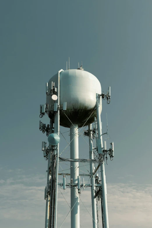 the large white water tower has multiple antennas