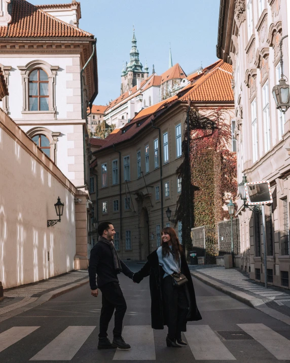 a couple walking down a street with many old buildings