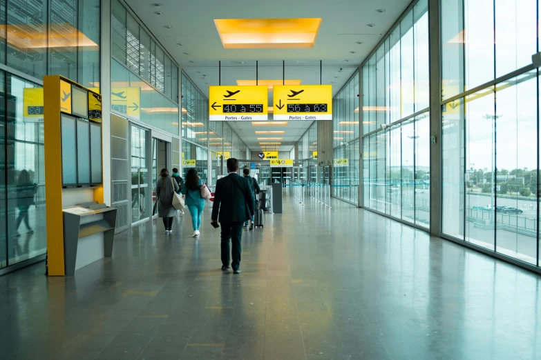 people walking down a walkway under yellow signs