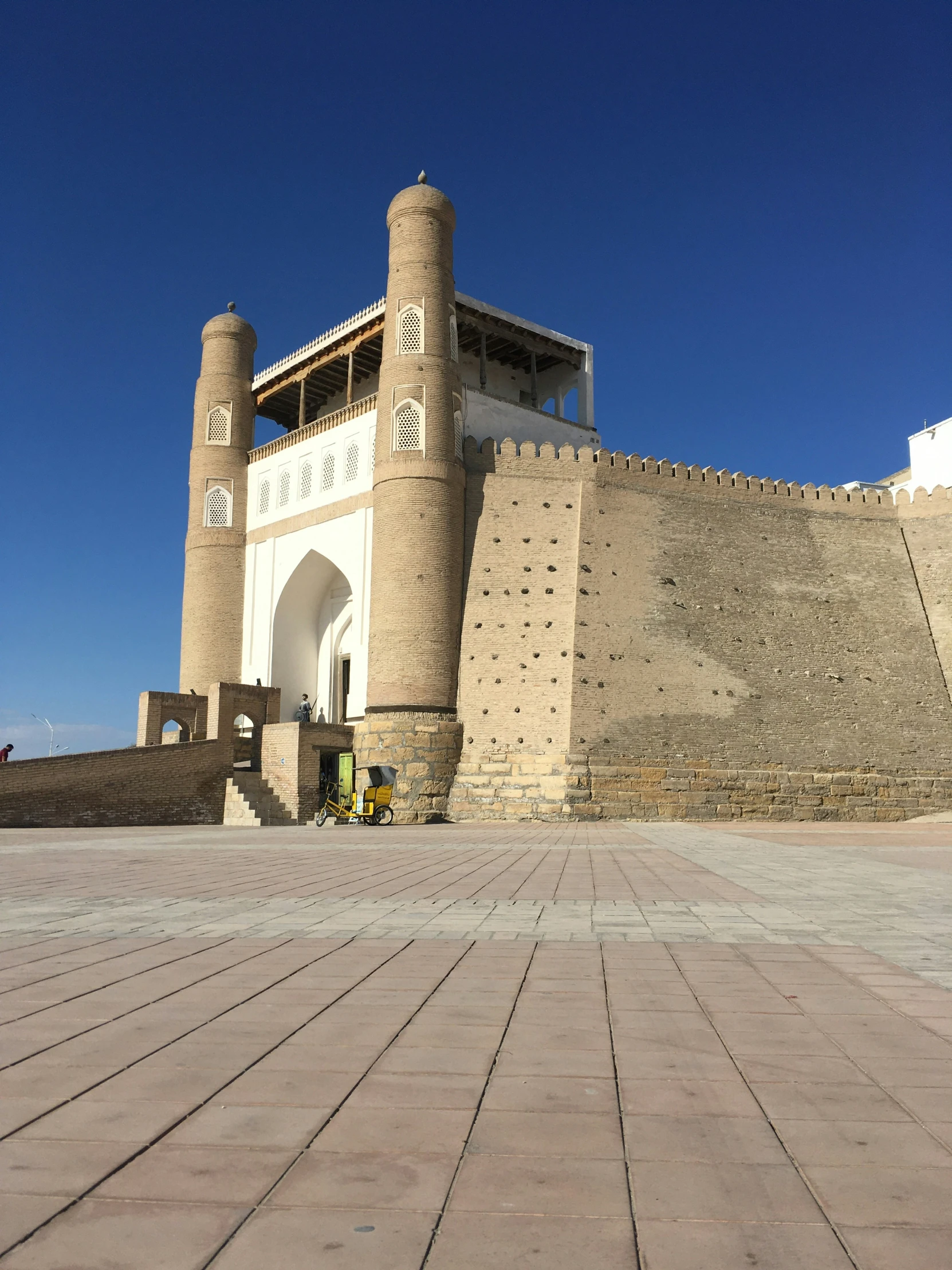 a bricked area with a white fence and building