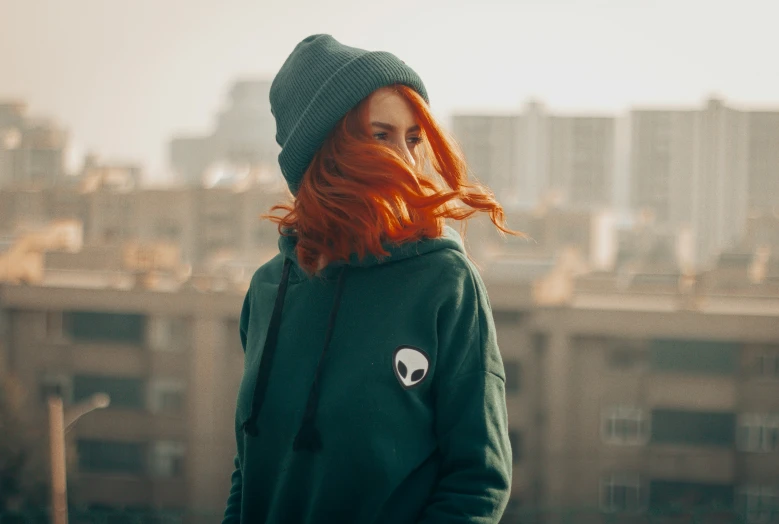 a woman wearing a green sweatshirt with a skull patch on the left side