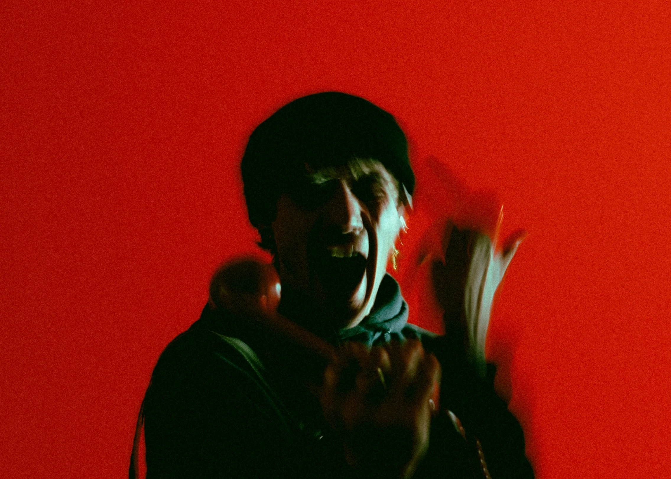 a man in front of a red wall holding up some bananas