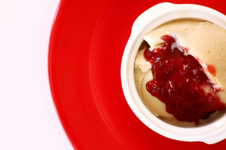 an ice cream dish with strawberry jelly on a red plate
