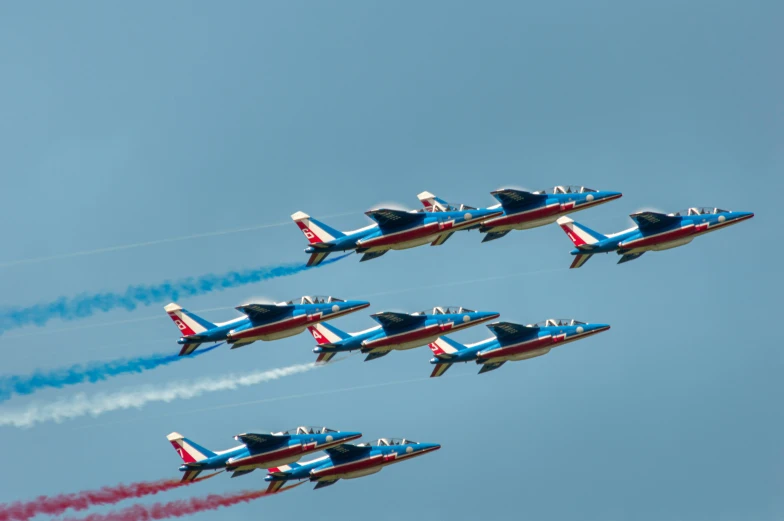 five fighter jets leaving colored smoke behind them