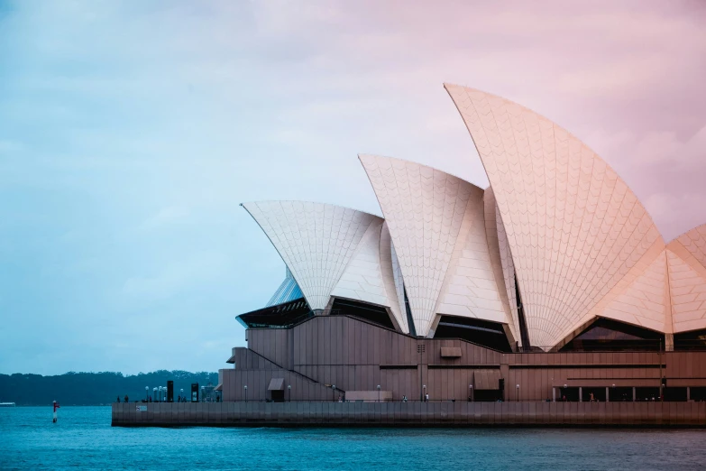 the sydney opera house is lit up with pink clouds