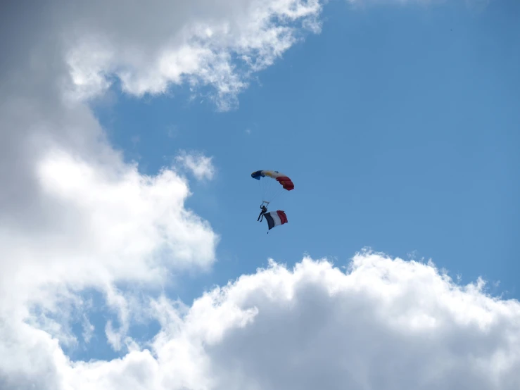 two parachutes flying in the sky above clouds