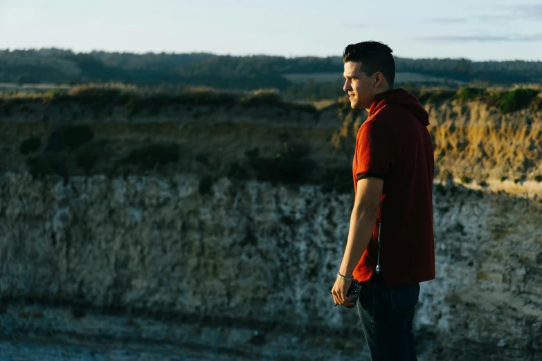 a young man standing next to a large cliff