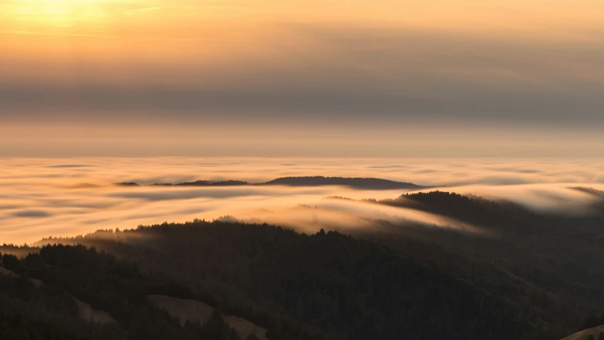 the sun shines in a valley below the clouds