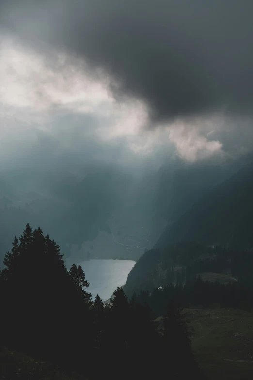 a dark grey sky with rain, clouds and a boat