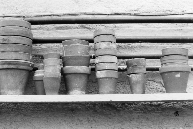 a wooden shelf with pots that are lined up on it