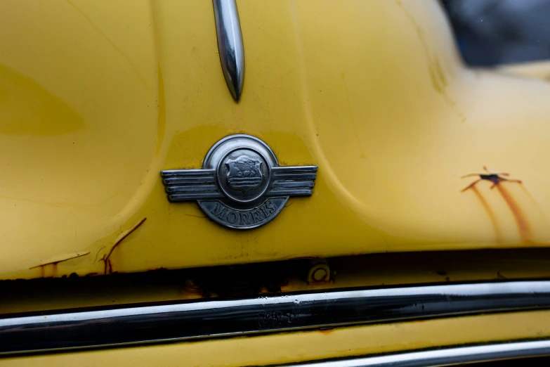 the emblem of a yellow classic car on a rusty looking old car