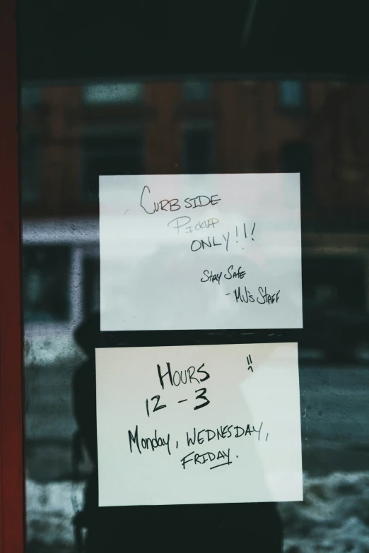 two different handwritten signs displayed in a window