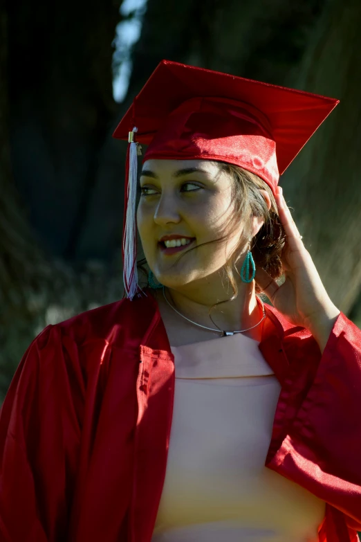 a smiling young female student wearing a red graduation cap