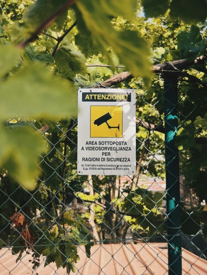 a warning sign posted by a fence for the public