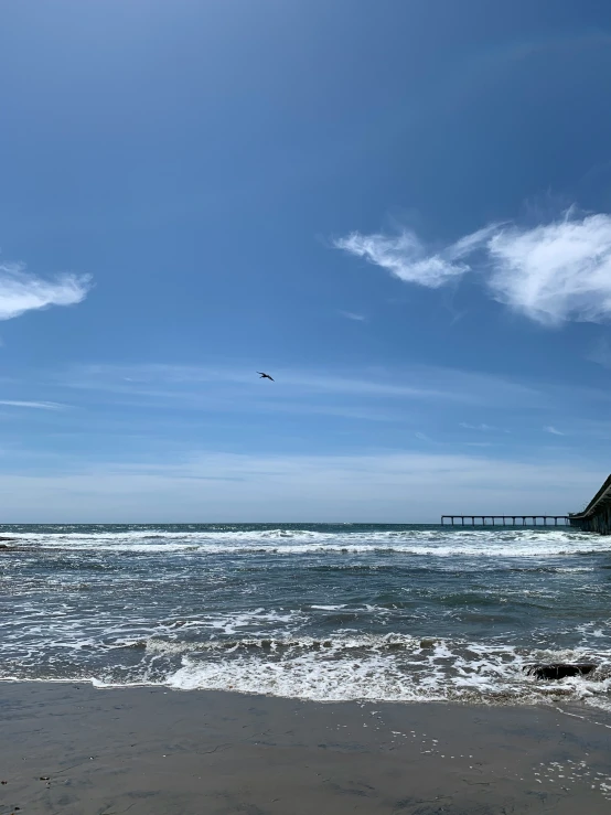 a lone bird flying in a blue sky above the ocean