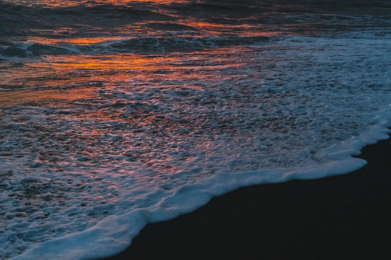 the sun shining on a beach and waves breaking at shore