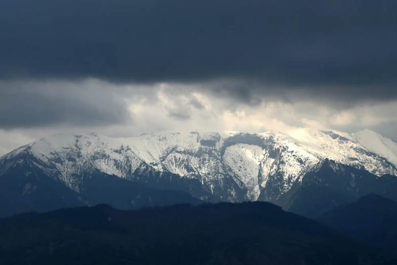 the mountains are covered with snow under clouds