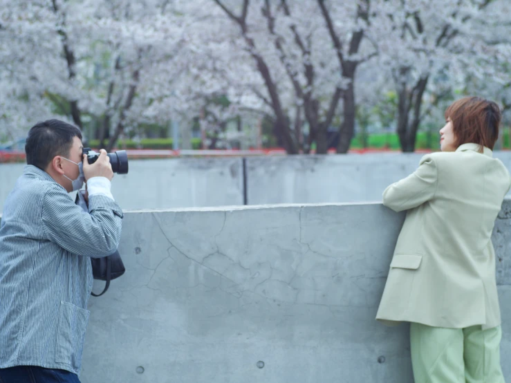 two people are taking pictures next to a wall