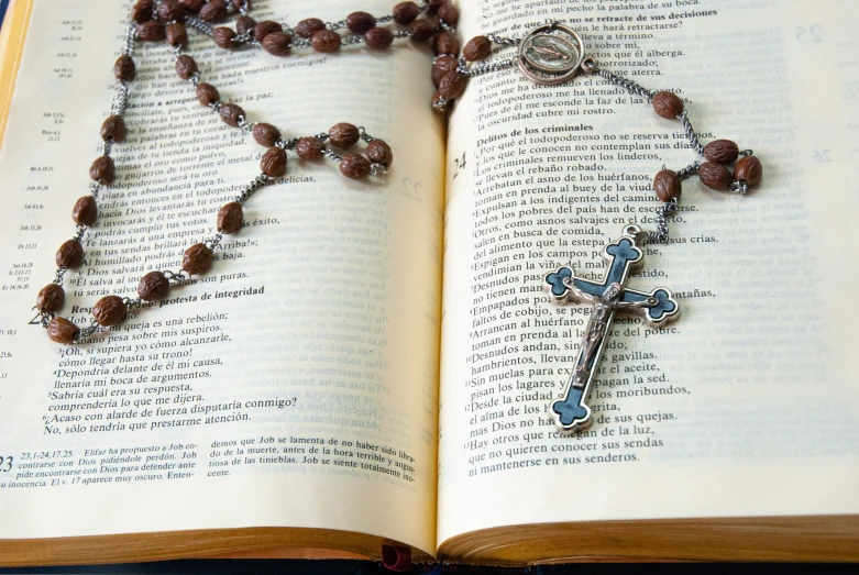 a rosary on a book is next to an empty cross