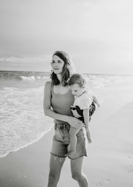 a woman carrying a child on the beach