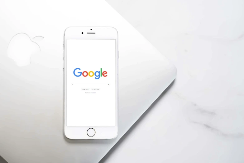 an iphone sitting on top of a desk with google written on it