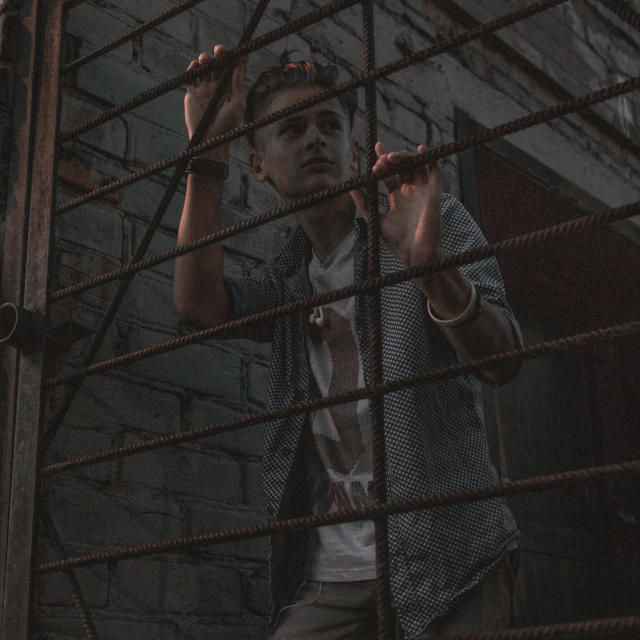 a man making hand gestures while standing behind bars