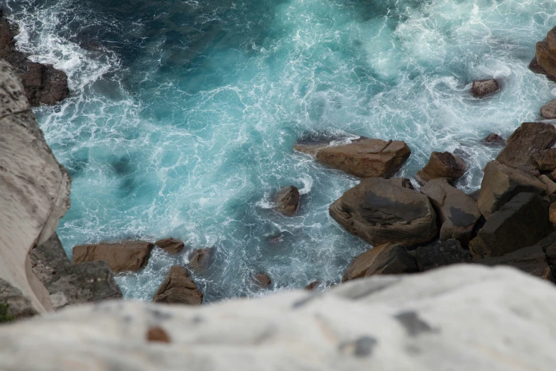 an aerial view of waves crashing into the rocky shore