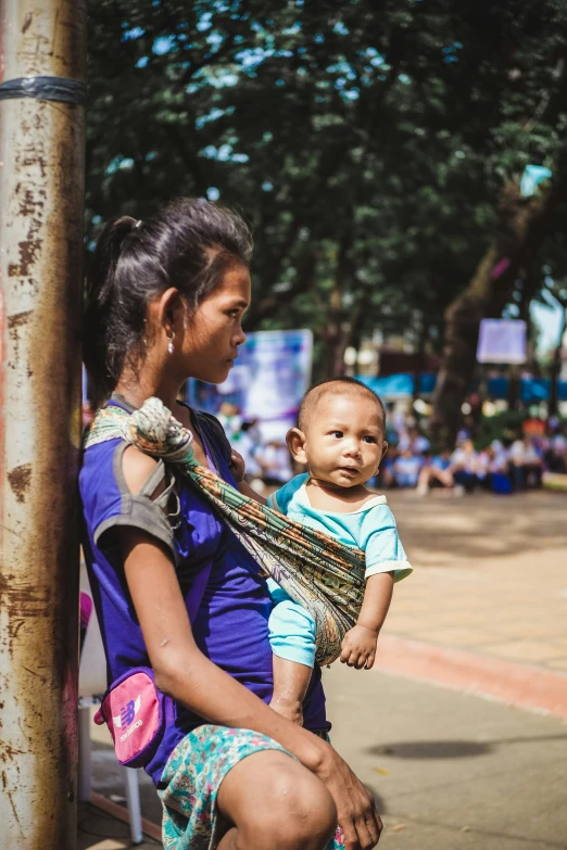 a woman with a child on her lap standing near a pole