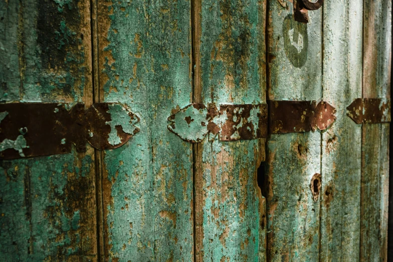 an old blue and rusted metal door with brown and white latches