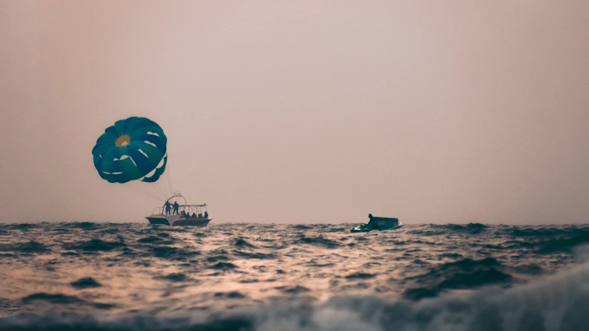 a couple of people on boats and parachutes in the ocean