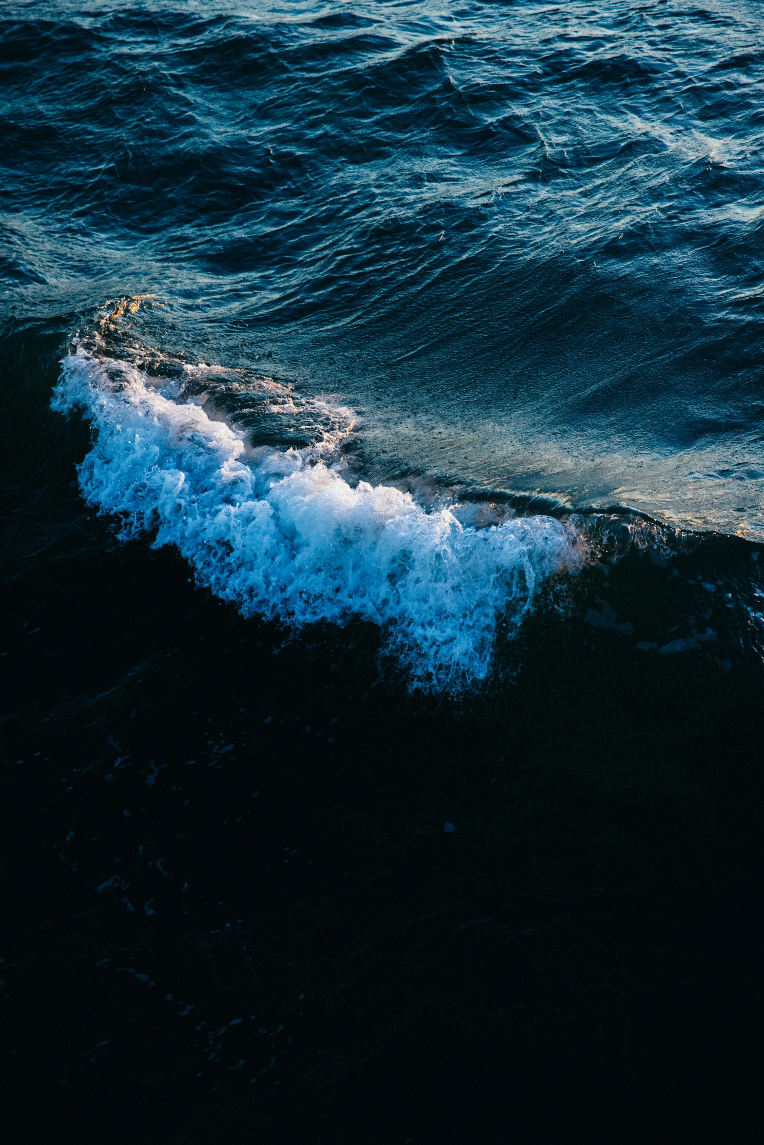 a wave coming towards a beach area in the middle of the ocean