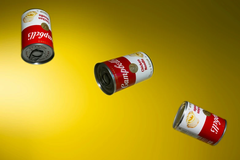 three cans of different kinds of soda on a yellow background