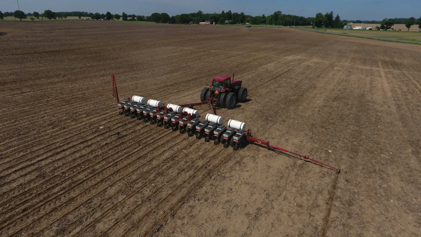 a large plow with a red frame is on a farm land