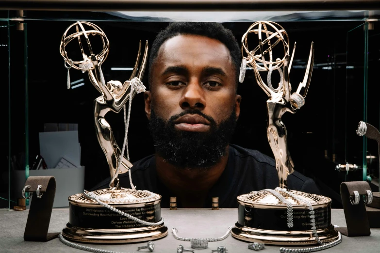 a man sitting next to three trophies that are on display