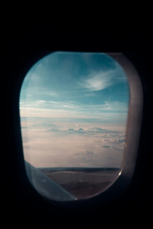 view from an airplane window of clouds and a plane wing