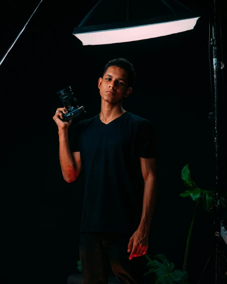 a young man stands holding an analog camera