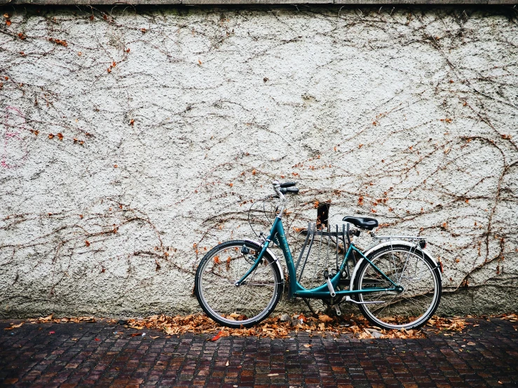 a blue bike parked next to the side of a white wall