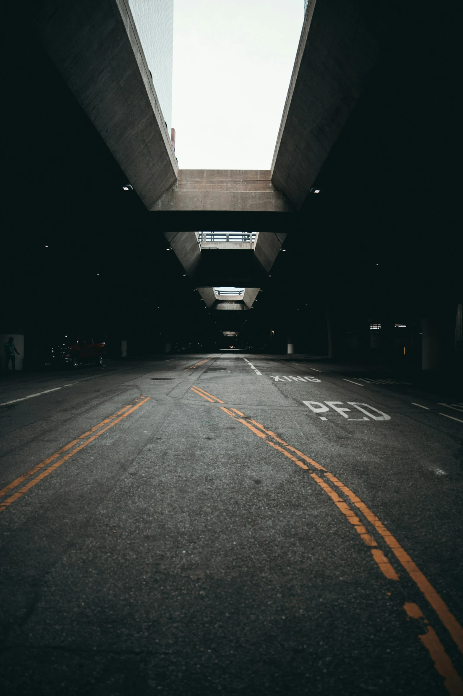 an empty street under a bridge with cars going underneath it