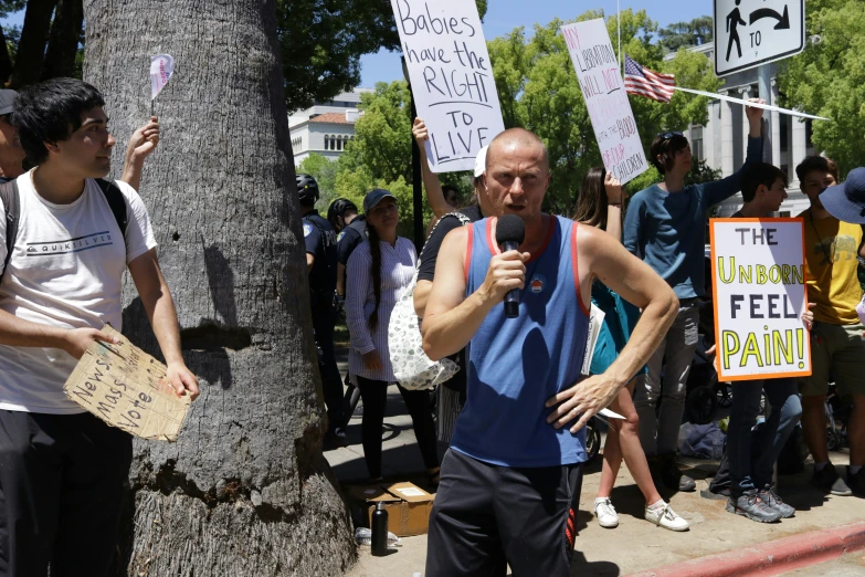 a man is holding a microphone as people stand near