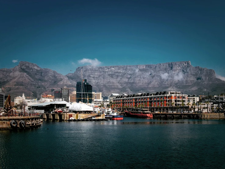 a mountain range rises in the background over a city by the water