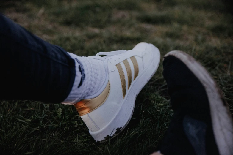 a person's feet in white sneakers in the grass