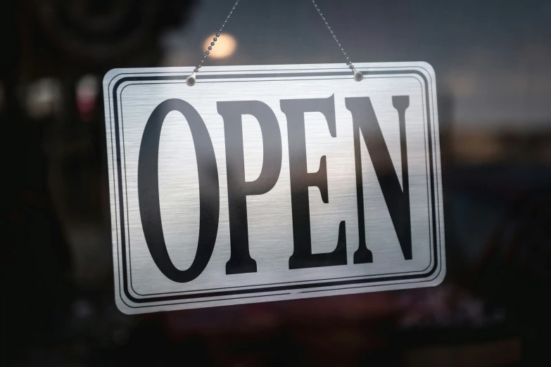 a sign hangs on a glass door with the word open