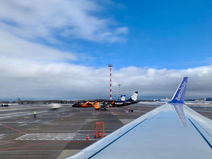 airplane wing at the airport with airplane and building nearby