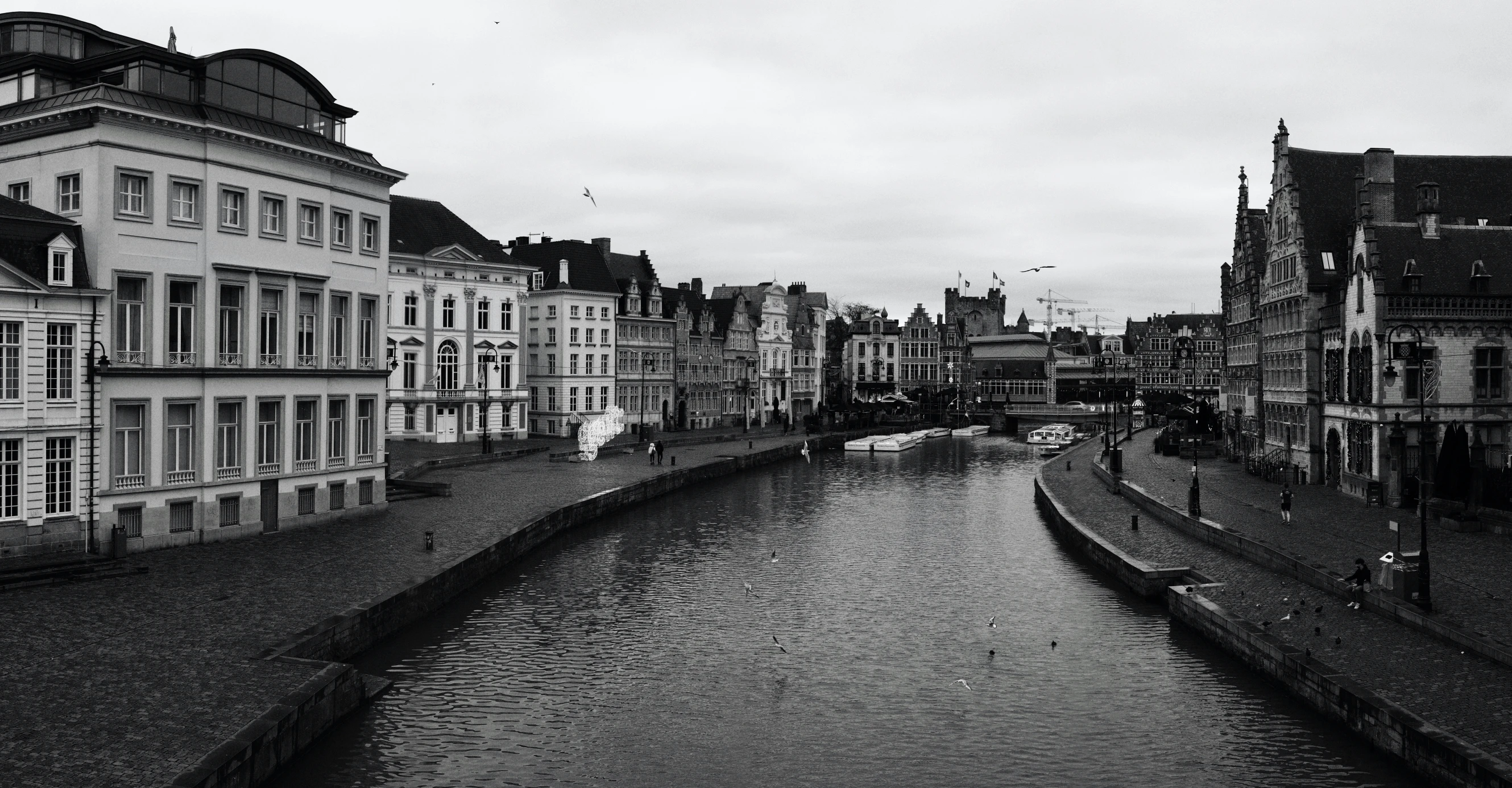 several old buildings line a river with a bridge over it