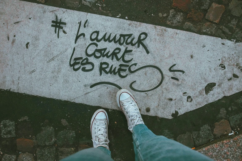 a person with white shoes standing on the sidewalk