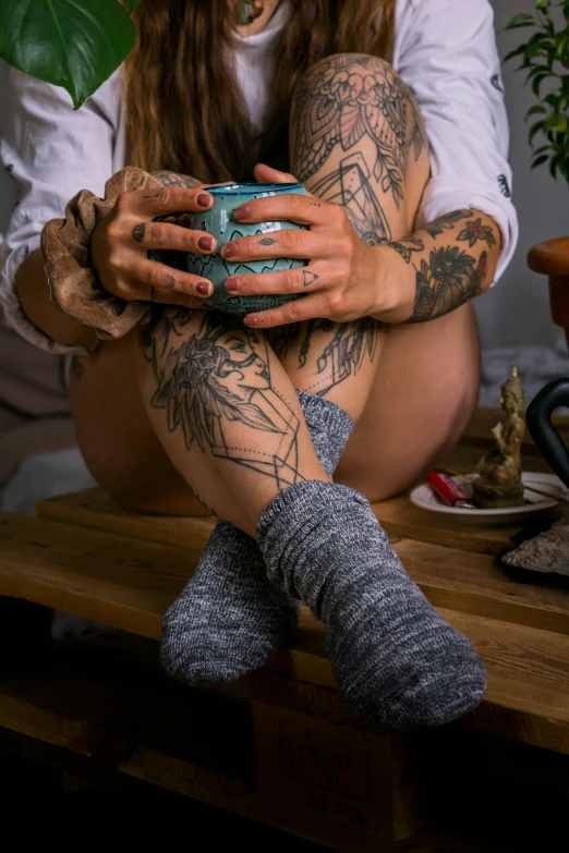 girl with tattoos and leg socks holding a cellphone