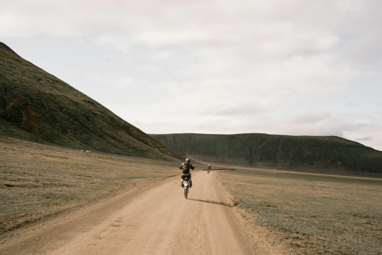 a man is riding down the middle of a dirt road