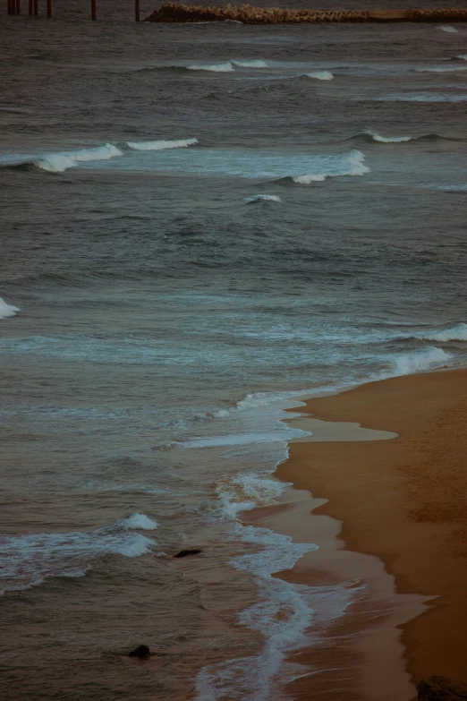 a person sitting on the sand near the ocean