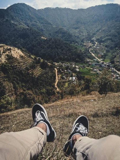 a pair of feet on the ground in front of some hills and a town