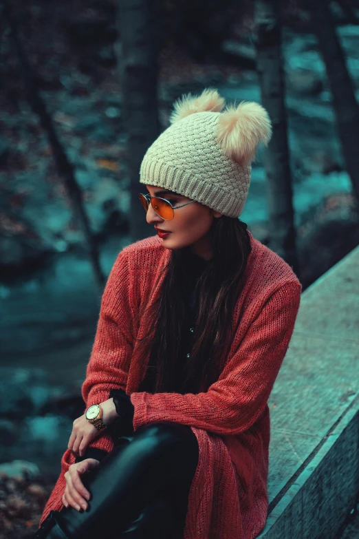 a woman is sitting down wearing a hat